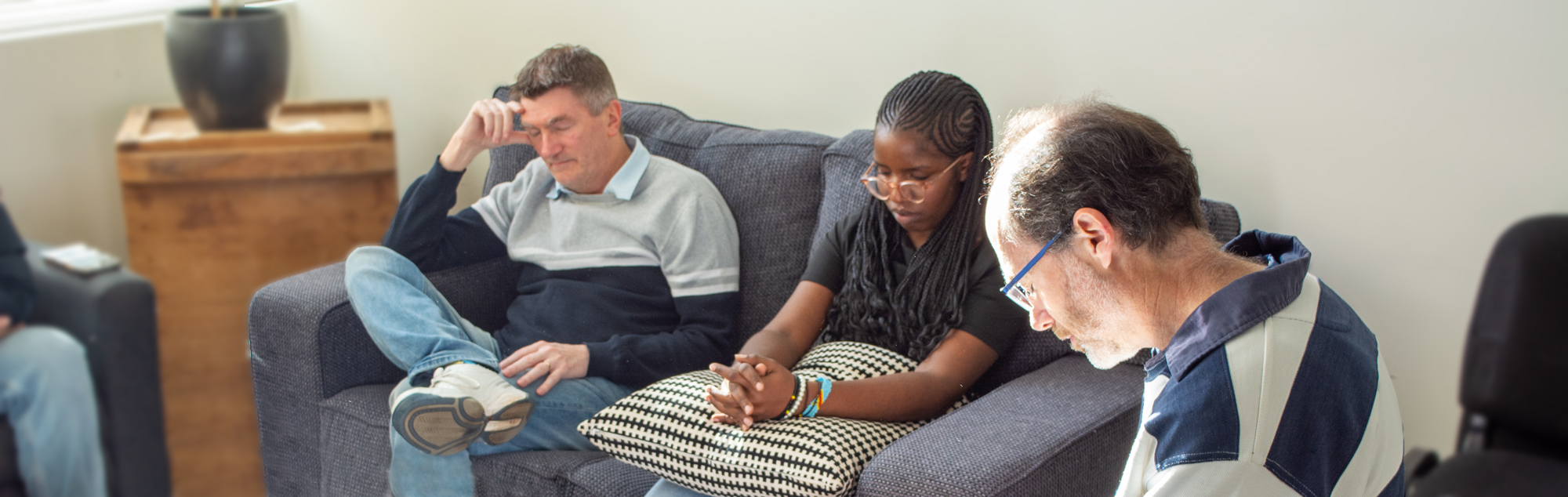 Members of the worship team sit together heads bowed and eyes closed as they pray together.