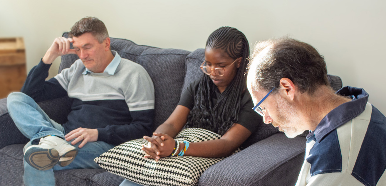 Members of the worship team sit together heads bowed and eyes closed as they pray together.