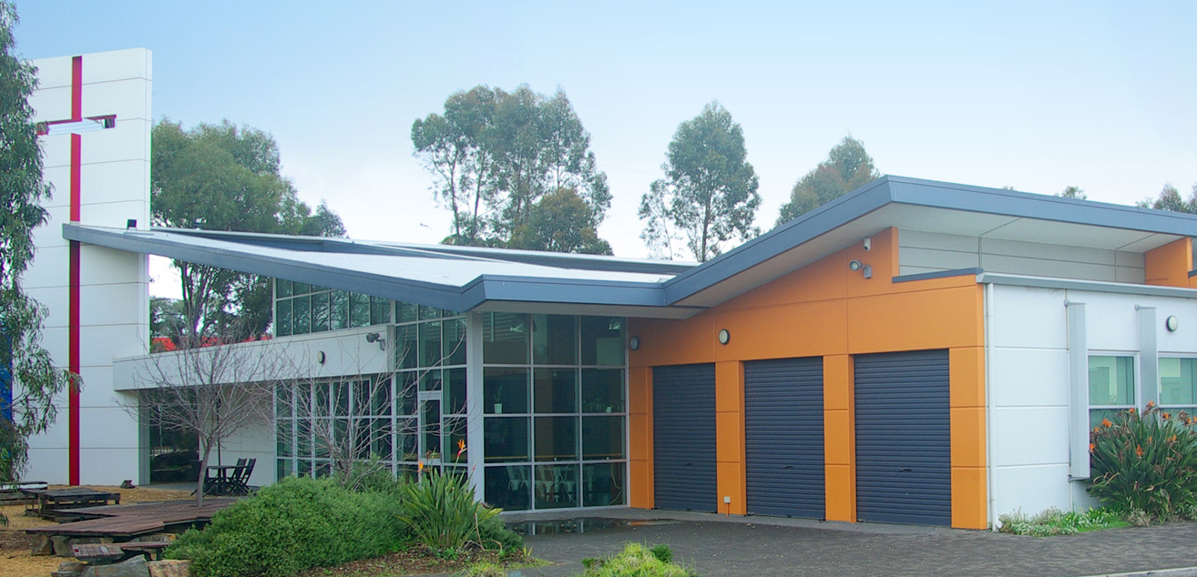 The church building stands tall and proud as the large cross on the front of the building reaches out towards the sky. The church is surrounded by trees and shrubs in a native garden.
