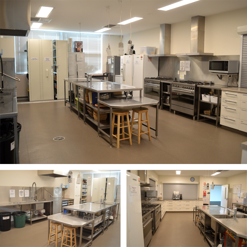 A large stainless steel kitchen fitted with appliances featuring a big island in the center of the room. Ovens and fridges run along on wall, with pantry cupboards along the back, and dishwasher and sink on the other. A large bench with opening window allows the kitchen to be opened to the foyer for food service.