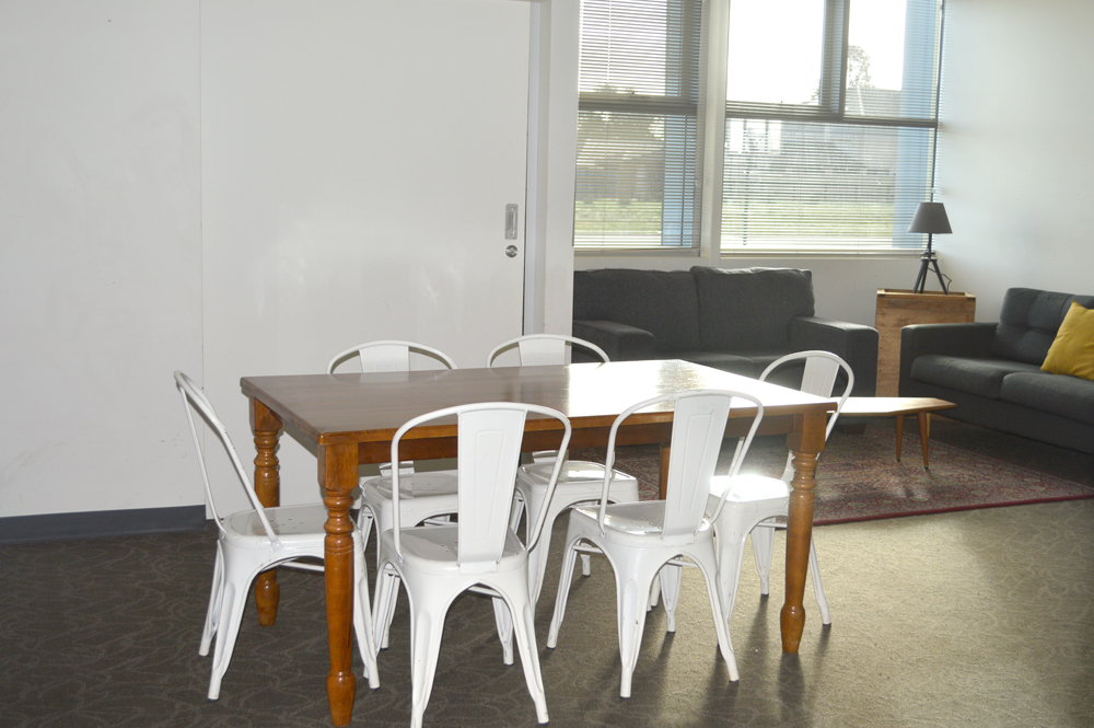 The meeting room is setup with a table surrounded by chairs, with couches lining the walls.